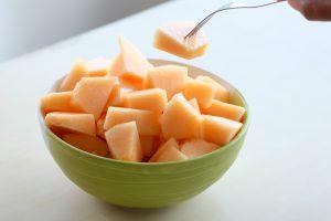 The hands of the people are using the fork to melt the orange Melon. Sweet taste Sliced in a ceramic bowl